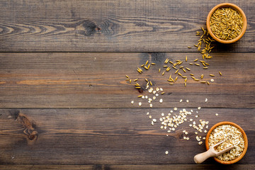 Oatmeal and oat in bowls on dark wooden background top view copy space