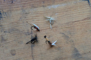 Wet and Dry artificial fishing lures and fly's sit on a wooden table getting readyi for opening season for sports fishing