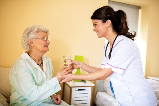 Nurse brings water to old patient
