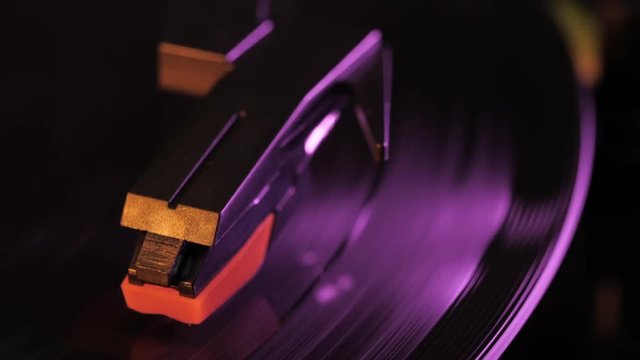 Record player turntable HD stock footage. A record player turntable with it's stylus running along a vinyl record. Neon violet light