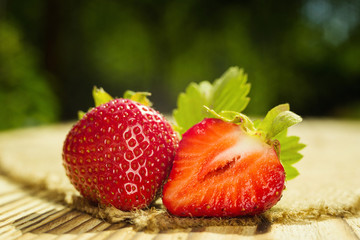 strawberries on wooden table in natural background, delicious first class organic fruit as a concept of summer vitamins