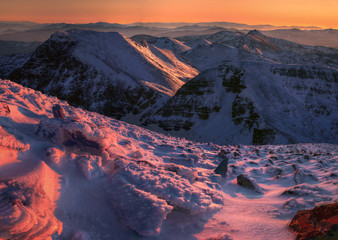 The sunset dyes orange and violet the snowy peaks