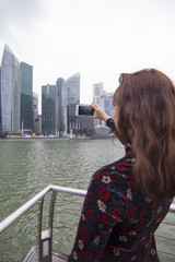 Fototapeta na wymiar A young Asian woman taking a picture of the city.