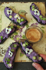 Crostini aus schwarz eingefärbtem Brot mit lila Vitelotte Krtoffel-Frischkäse Aufstrich, Zwiebellauch und Hornveilchen