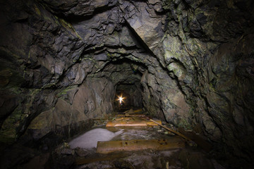Underground abandoned gold ore mine shaft tunnel gallery with green rocks