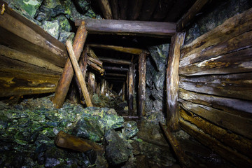 Underground abandoned gold ore mine shaft tunnel gallery with wooden timbering