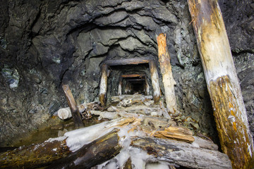 Fototapeta na wymiar Underground abandoned gold ore mine shaft tunnel gallery with wooden timbering