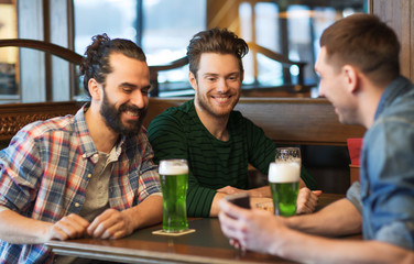 friends with smartphone drinking green beer at pub