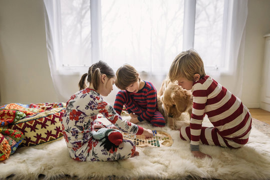 Three children sitting on the floor playing a board game