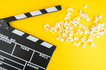 Fototapeta na wymiar Cinema minimal concept. Watching film in the cinema. popcorn, clapper board on yellow background 