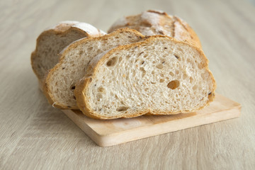  TWO CRUSTY SLICED BREAD ON CUTTING BOARD
Two brown crusty sliced french loaf on cutting board is placed on a wood table.