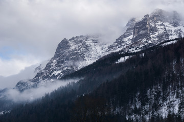Dramatic, mysterious landscape with mountains shrouded in fog and clouds in the winter. Shot in the Austrian Alps near the town of Waidring