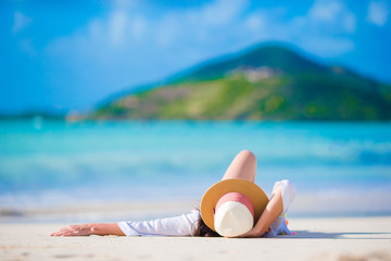 Fototapeta na wymiar Young woman enjoying the sun sunbathing by perfect turquoise ocean.