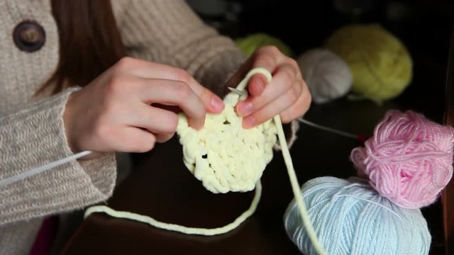 Young woman knits with needles and colored yarn in winter