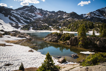 A lake surrounded by snow with snow covered mountains in the background in Colorado. 