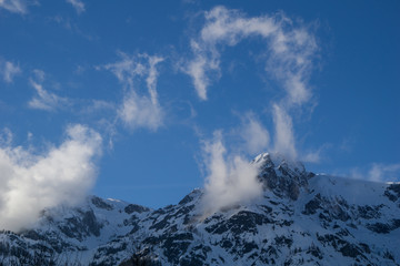 Mountain peak and clouds meet high up in the Austrian alps on a sunny winter day
