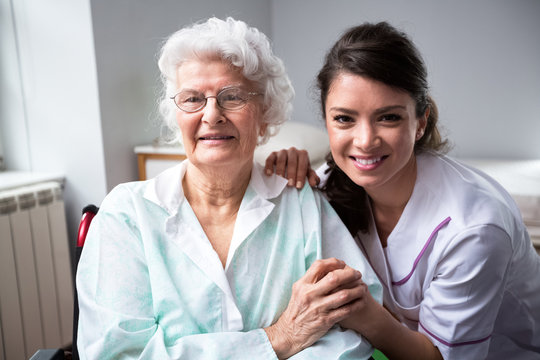 Smiling nurse and old woman patient at wheelchair