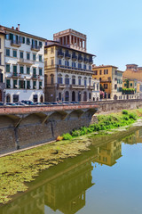 Fototapeta na wymiar Buildings on the banks of the Arno River in the city of Florence. Italian architecture. Urban landscape in Italy. Reflections on water. June 2017.