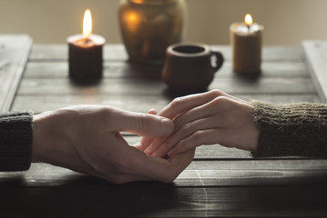 Romantic evening by candlelight lovers. Hands of a man and a woman are hugging each other.