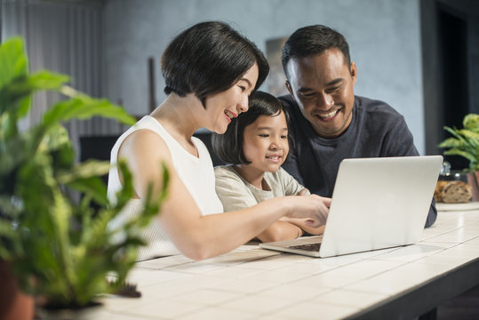 Happy Asian Family Using The Computer Together At Home.