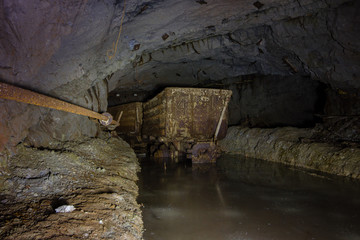 Underground abandoned ore mine shaft tunnel gallery with wagon ore cart