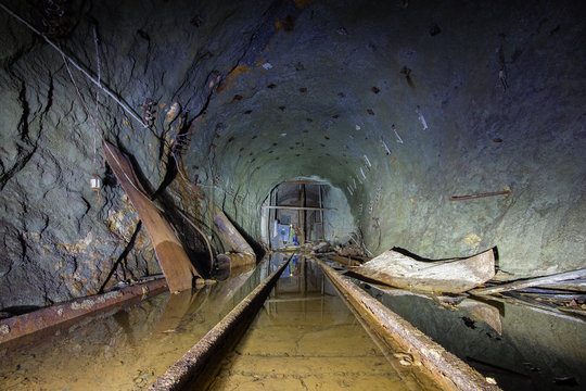 Underground abandoned ore mine shaft tunnel gallery with tails