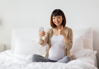 Obraz na płótnie Canvas pregnant woman taking selfie by smartphone at home