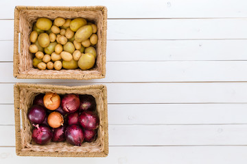 Two wicker baskets with fresh potatoes and onions