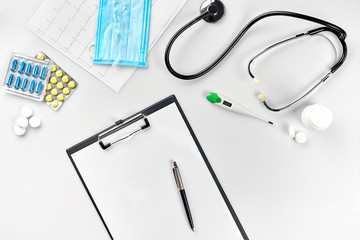 Business set for hospital: pills, stethoscope, medical equipment, note book with pen and mask on white background. Modern doctor's set on the table.