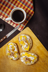 A cup of coffee with pineapple sandwiches, on a black, textured table. Breakfast.