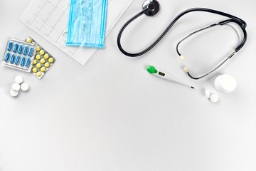 Medical equipment : pills, mask, thermometer and stethoscope on white background. Top view. Copy space