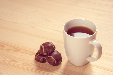 a Cup of black tea and chocolates. background. table.