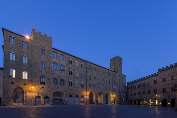 Fototapeta premium Pretorio Palace and Porcellino Tower, Priori square in a quiet moment of the evening in the blue light, Volterra, Pisa, Tuscany, Italy