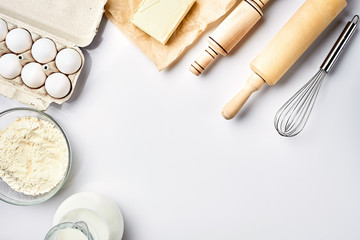 Preparation of the dough. A measurement of the amount of ingredients in the recipe. Ingredients for the dough: flour, eggs, rolling pin, whisk, milk, butter, cream. Top view, space for text