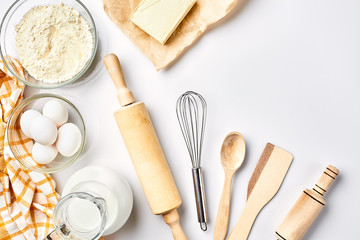 Preparation of the dough. A measurement of the amount of ingredients in the recipe. Ingredients for the dough: flour, eggs, rolling pin, whisk, milk, butter, cream. Top view, space for text