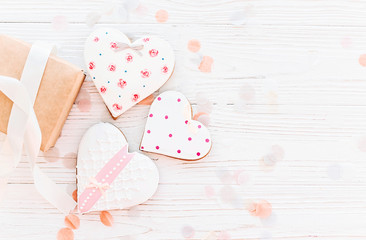 happy mother's day greeting card. cookie hearts and craft gift box on white rustic wooden background with confetti flat lay. space for text. happy valentine's day or women's