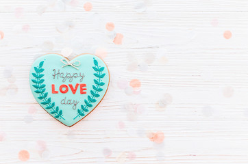 happy valentine's day greeting card. happy love day text on cookie heart on white rustic wooden background with confetti flat lay. space for text . mock-up
