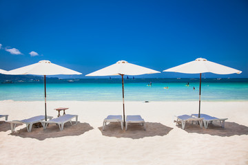 Tropical vacation on white sand beach with sun, blue sky and palm trees. White beach at Boracay, Philippines.