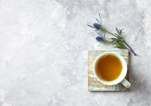 Cup of Tea and Sea Holly Flowers on gray stone background