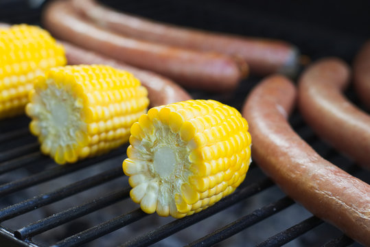 Corn cob and sausages on grill 