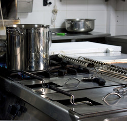 Large steel professional pan on the stove with fire in the restaurant kitchen
