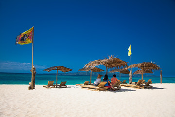 Relaxing couch chairs with straw parasol on Puka sandy beach, Boracay. Philippines.