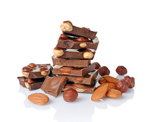 Close-up pieces of chocolate bar with whole hazelnuts and almonds