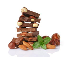 Close-up pieces of chocolate bar with whole hazelnuts, almonds and mint
