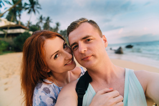 happy lovers take pictures of themselves on the beach