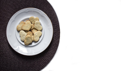 on a white background on a dark napkin is a plate with cookies in the form of a heart 