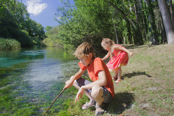 Siblings summer recreation activity outdoor game on Italian Tirino river bank in sunny day