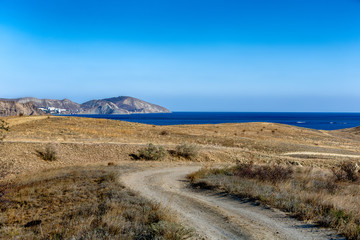 View on the sea and a protruding mountain cape. Blue cloudless sky.