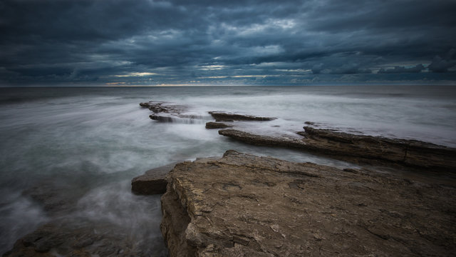 Beautiful rocky beach in the Portuguese coastline in a stormy day. Seascape. Long exposure