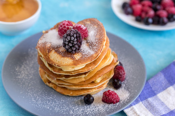 Fluffy and delicate pancakes with powdered sugar and berries.